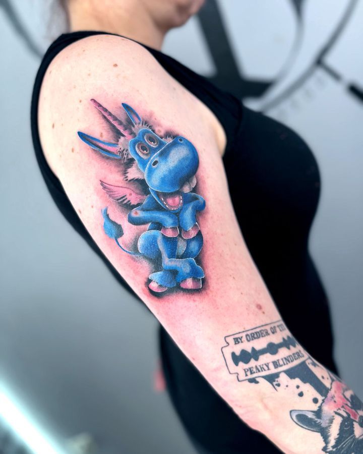 Farbige Comicfigur in Blau und Rosa auf dem Oberarm