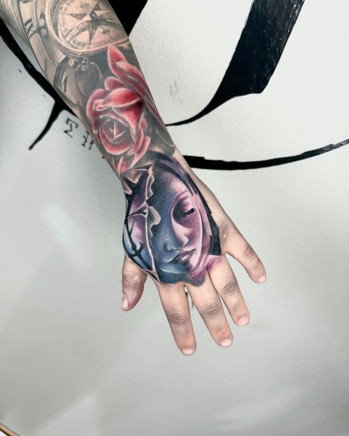 Farbiges Tattoo mit roter Rose und Frauengesicht auf dem Handrücken