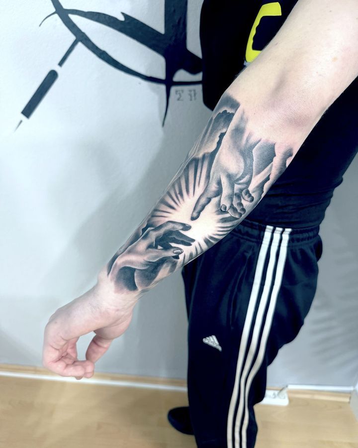 Surreales Black-and-Grey-Tattoo mit Händen und Lichtstrahlen auf dem Unterarm